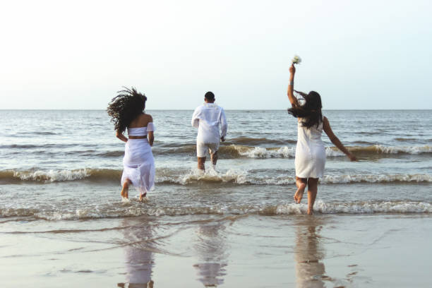 Happy friends celebrating reveillon on the beach, running to the sea and jumping waves. Paraiso beach, Mosqueiro Happy friends celebrating reveillon on the beach, running to the sea and jumping waves. They wear white clothes. Group of young people enjoying and partying together. Happiness, togetherness, youth and new year's eve concepts. Paraiso beach, Mosqueiro wave jumping stock pictures, royalty-free photos & images