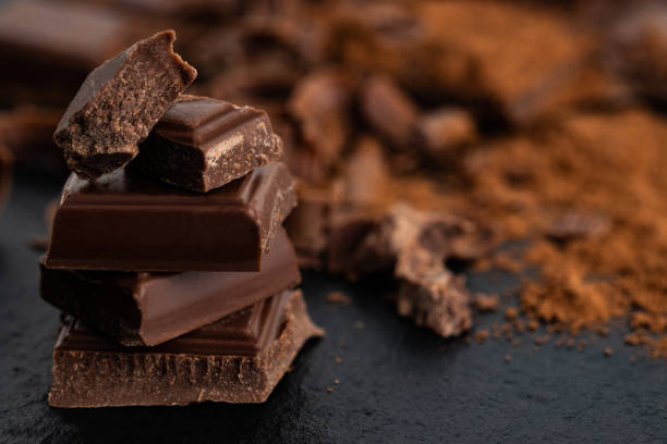 istock Broken chocolate pieces and cocoa powder on a dark background 1087565902