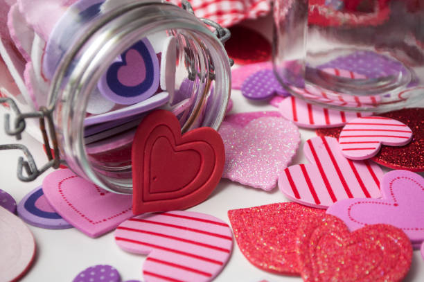 istock pink and red hearts falling  from glass container on white background - valentine's day concept 1087566286