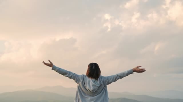 Young woman arms outstretched relaxation and freedom on Top Mountain