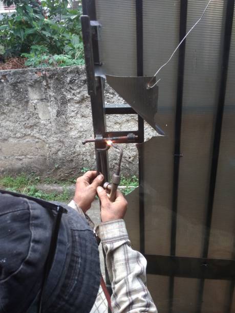 istock Old Man Welding a Corrosive Black Iron Handle of Gate 1087575764