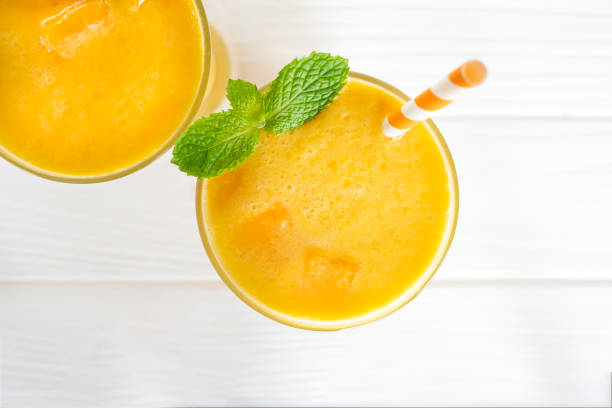 Mango smoothies yellow colorful fruit juice milkshake blend beverage healthy high protein the taste yummy In glass drink to lose weight drink episode morning white background from top view