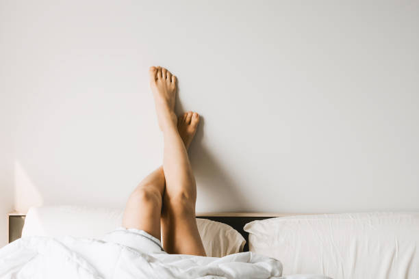istock Woman's legs in bed on the white wall, resting or morning concept, selective focus 1087580086