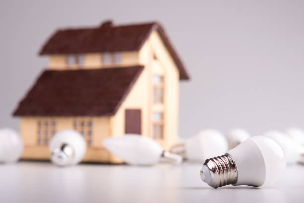 lámpara led mentira cerca el diseño de la casa sobre un fondo blanco. tema ahorro de energía en la casa - piggy bank savings investment glasses fotografías e imágenes de stock