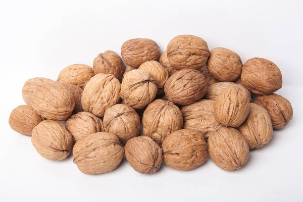 istock Whole unpeeled and broken walnuts on white background. 1087591854