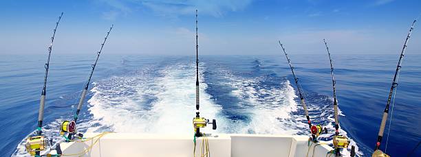 Boat trolling the sea with rod and reels boat fishing trolling panoramic rod and reels blue sea wake prop wash freshwater fishing photos stock pictures, royalty-free photos & images