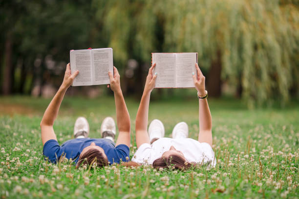 istock Relaxed young couple reading books while lying on grass 1087602630