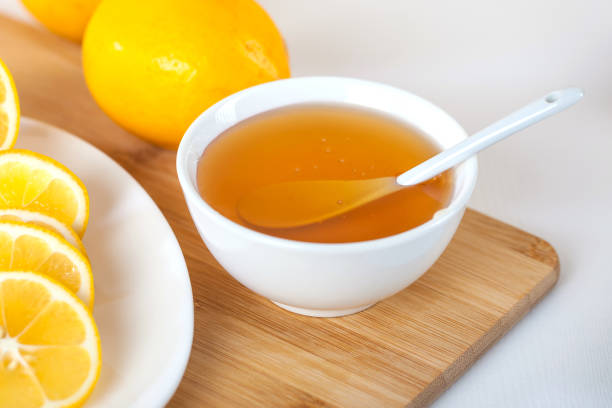 istock honey in a white ceramic bowl with spoon and lemon on a wooden kitchen board 1087605932