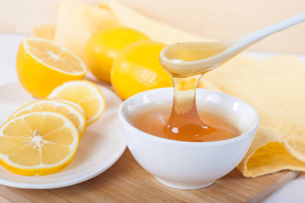 istock honey in a white ceramic bowl with spoon and lemon on a wooden kitchen board 1087605942