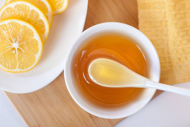 istock honey in a white ceramic bowl with spoon and lemon on a wooden kitchen board 1087605946