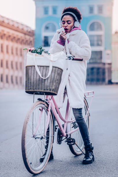 So cold. Serious brunette female sitting on bicycle while spending weekend outdoors