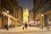 Illuminated cityscape of Zrinyi Street in Budapest with St Stephen's Basilica in a snowy winter landscape at dusk