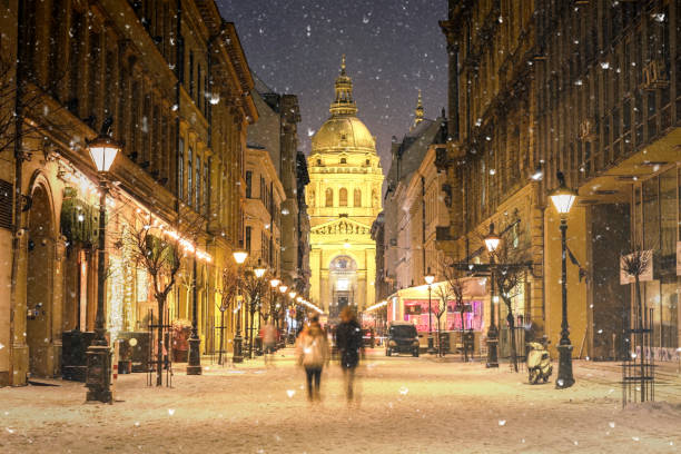 Illuminated cityscape of Zrinyi Street in Budapest with St Stephen's Basilica in a snowy winter landscape at dusk stock photo