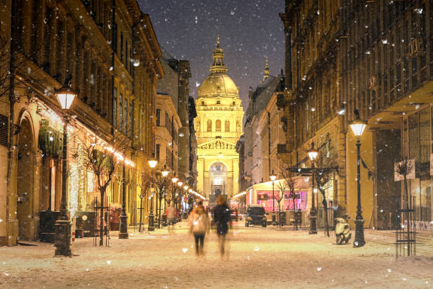 illuminated cityscape of zrinyi street in budapest with st stephen's basilica in a snowy winter landscape at dusk - hungary imagens e fotografias de stock