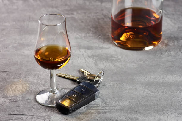 стекло и бутылка виски на каменном столешном столе и ключи от машины. вождение в нетрезвом виде - designated driver стоковые фото и изображения