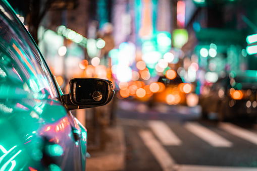 Reflections of city light during road trip travel at night -- focus on car rear view mirror