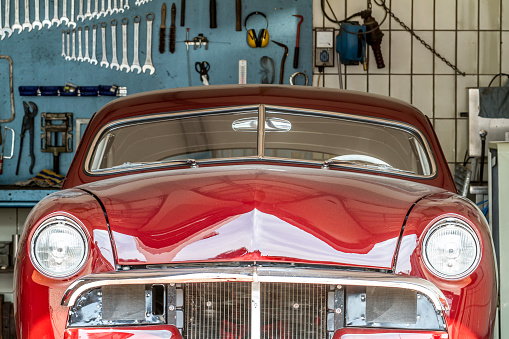 red old timer in a car repair shop in process in front of a wall with screw-wreches