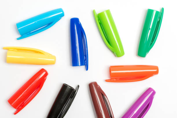 Bright colourful plastic pen lids randomly arranged on a white background