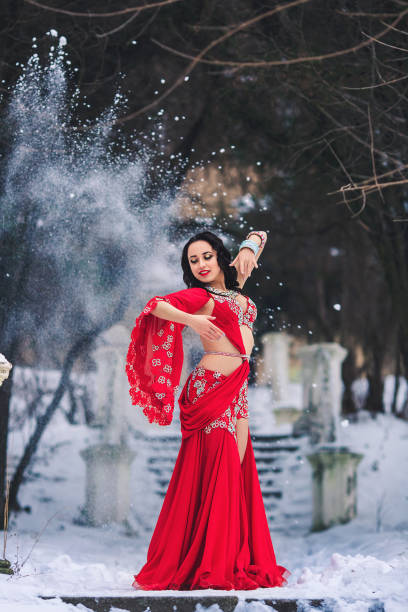 schöne junge mädchen tanzen bauchtanz im roten kleid im winter in einem park auf dem schnee. - arabia belly dancing dancing women stock-fotos und bilder