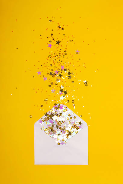 istock Colorful confetti scattered from envelope on yellow background. 1087671592