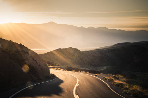 Highway at sunrise, going into Death Valley National Park Scenic view of Amargosa Mountains from highway travelling into Death Valley National Park. thoroughfare photos stock pictures, royalty-free photos & images