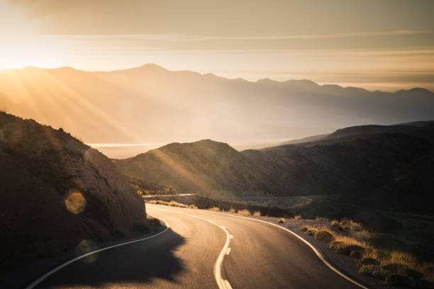 Highway at sunrise, going into Death Valley National Park Scenic view of Amargosa Mountains from highway travelling into Death Valley National Park. north america landscape stock pictures, royalty-free photos & images