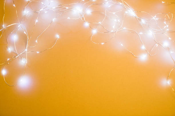 christmas lights on yellow background - luminant imagens e fotografias de stock