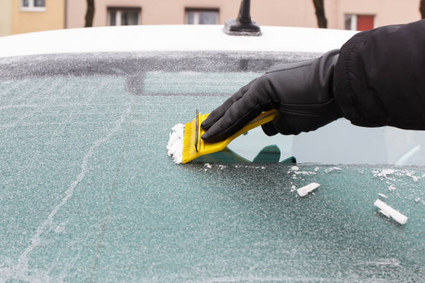 istock Hand holding scraper and removing ice or snow from car window 1087719114