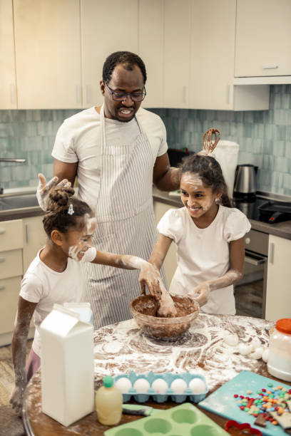 istock Two cute girls playing tricks while cooking with father at the weekend 1087722002