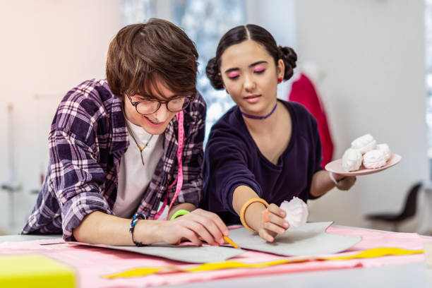 istock Young beautiful female asian designer and her colleague having break at work 1087730758