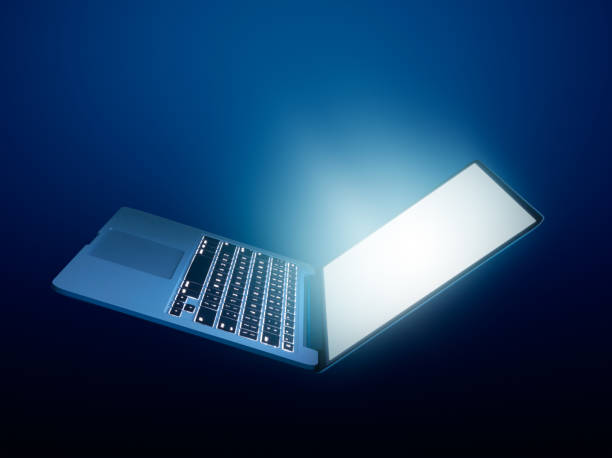 ouvert ordinateur portable avec l’éclatante lumière sur fond foncé - blue fin photos et images de collection