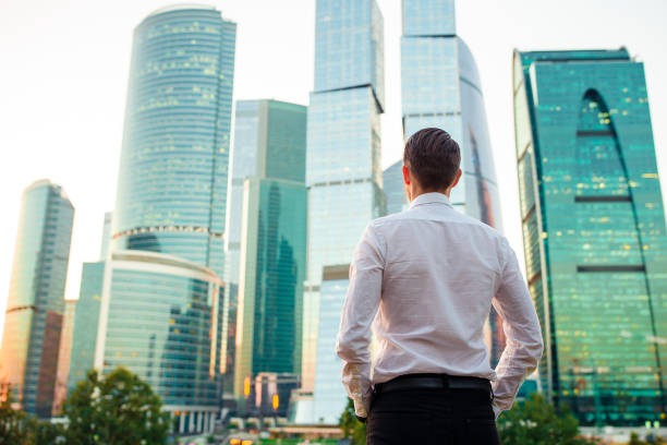 istock Back view of businessman looking on copy space while standing against glass skyscraper 1087735720