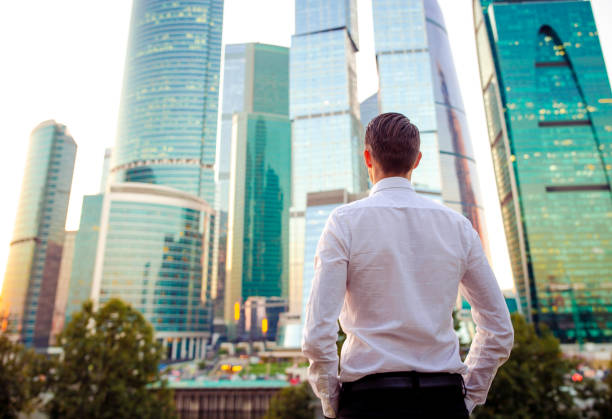 istock Back view of businessman looking on copy space while standing against glass skyscraper 1087735992