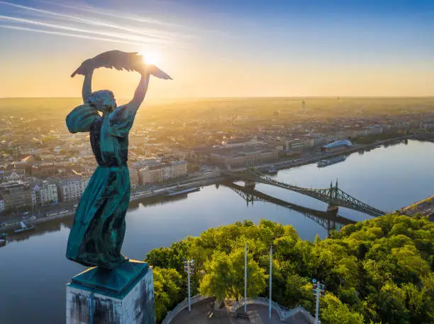 Budapest, Hungary - Aerial view from the top of Gellert Hill with Statue of Liberty, Liberty Bridge and skyline of Budapest at sunrise with clear blue sky