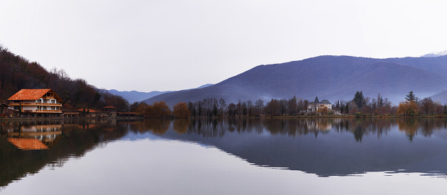 Mountain landscape panorama. The blue mountains covered with forests are reflected in still, calm water. Lake Lopota in Georgia.