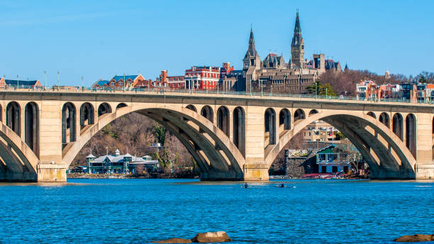 Washington DC, USA-August 21, 2015:  This tour boat and paddle boarder were spotted on the Potomac River at the Georgetown waterfront in Washington DC during summer.  Tour boats offer rides on the river and paddle boards can be rented.  The Watergate complex is in the background.