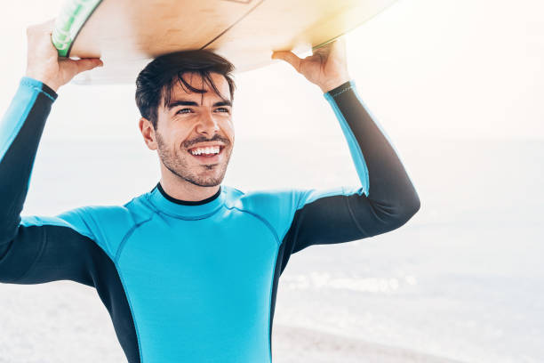 istock Young man with surfboard walking on the beach 1087792866