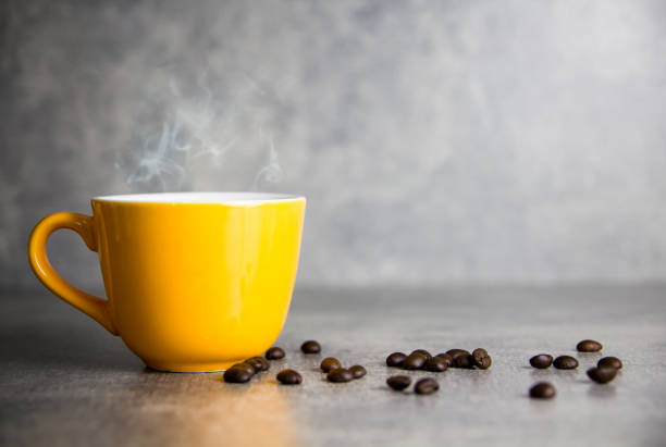 yellow cup of coffee and coffee bean with concrete background