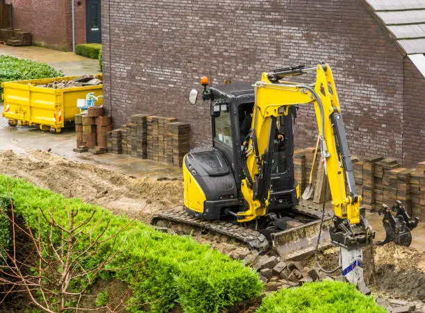 Photo of digger machine working on a garden construction in a modern neighborhood