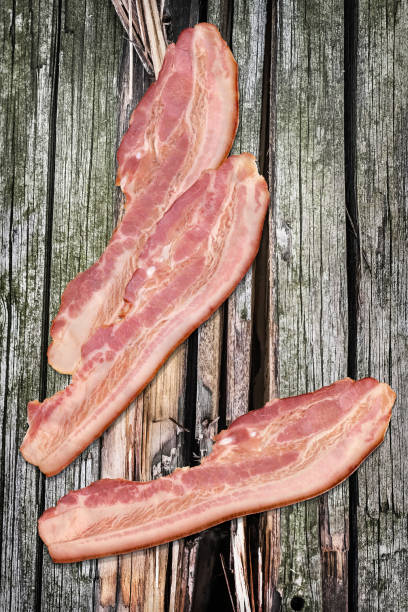 istock Three Pork Bacon Rashers Set On Old Knotted Weathered Cracked Pinewood Picnic Table Rustic Rough Grunge Surface 1087804222