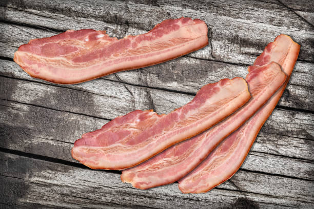 istock Four Pork Bacon Rashers Set On Old Knotted Weathered Cracked Pinewood Picnic Table Rustic Rough Grunge Surface 1087806580