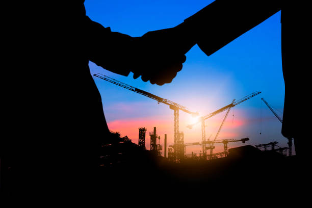istock silhouette shaking hands of investment people with engineer at working construction site 1087813188