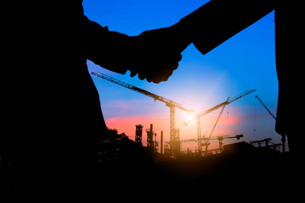 silhouette shaking hands of investment people with engineer at working construction site stock photo