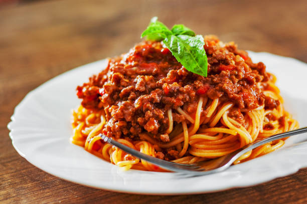boloñesa de espaguetis de pasta tradicional en plato blanco sobre fondo de mesa de madera - salsa de carne fotografías e imágenes de stock