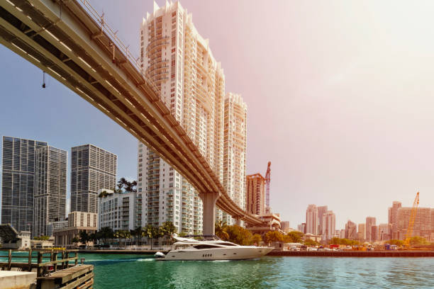 boot unter einer brücke am miami river vorbei. - apartment skyscraper florida architecture stock-fotos und bilder