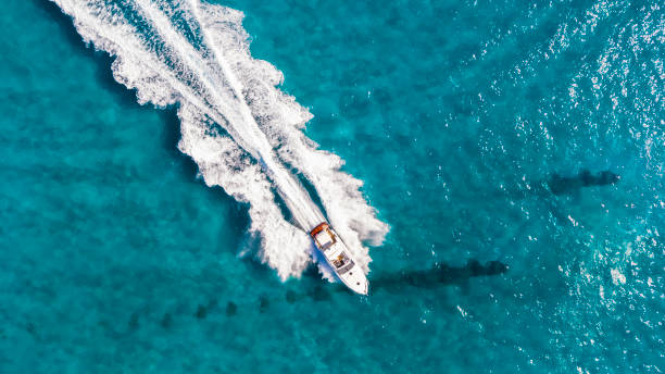 Aerial view of Yacht cruising over turquoise water Drone view above yacht cruising through flat calm blue Mediterranean water. racing boat photos stock pictures, royalty-free photos & images