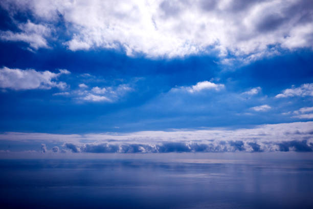 istock Deep blue flat calm sea and deep blue sky with white fluffy clouds 1087851672