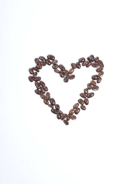Red velvet background with a heart-shaped hole with roasted coffee beans inside