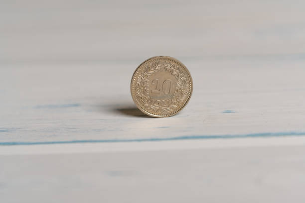une pièce de 20 centimes suisses debout sur un fond en bois - swiss currency coin swiss francs swiss coin photos et images de collection
