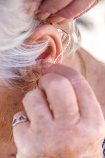 istock senior woman inserting hearing aid in her ears 1087882192